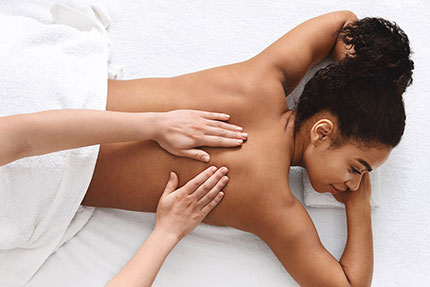 female person of color laying prone getting a back massage